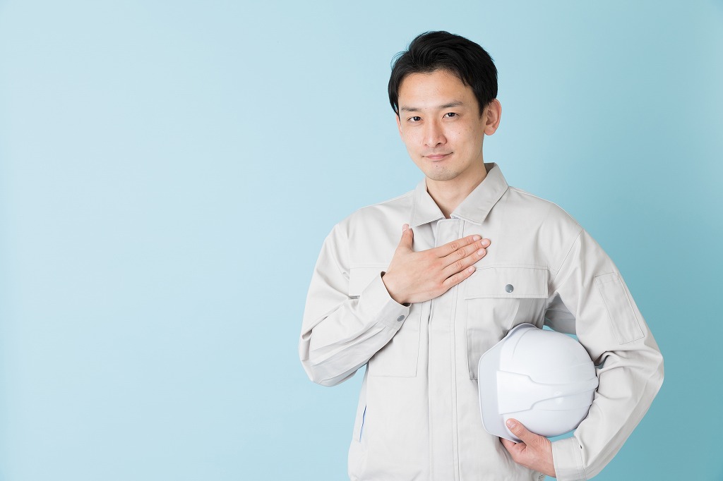 胸に手を当てる作業着姿の男性